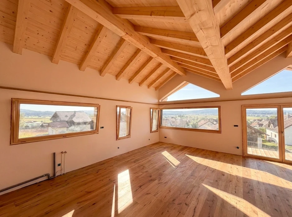 Intérieur lumineux d'un comble aménagé vide, vue panoramique sur village et campagne