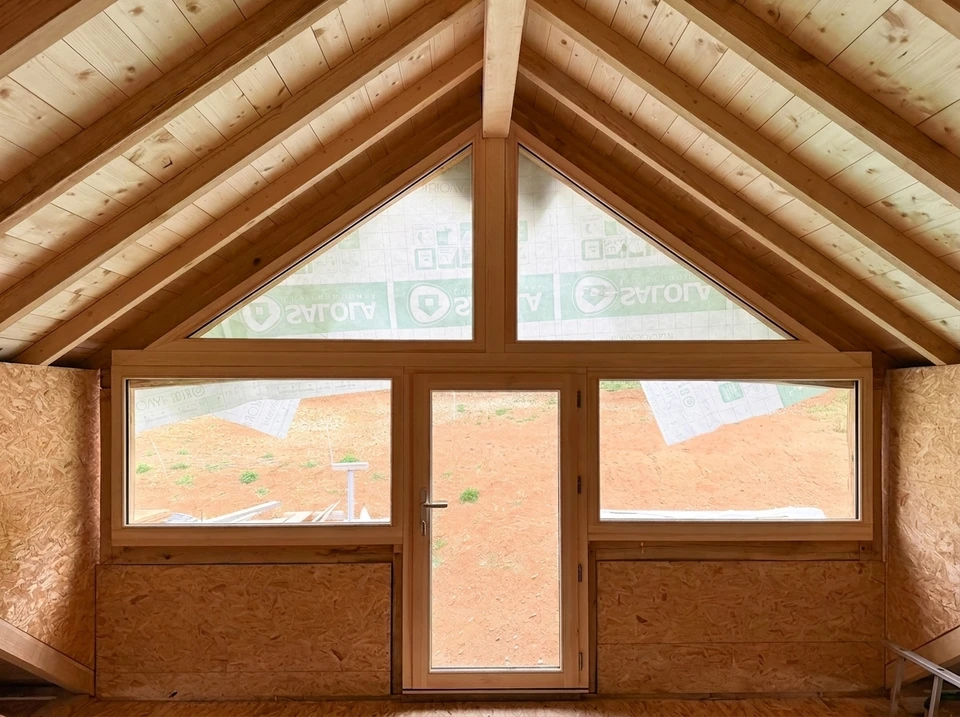 Intérieur d'un chalet en bois avec grande fenêtre à double vitrage, encadrée de bois naturel clair