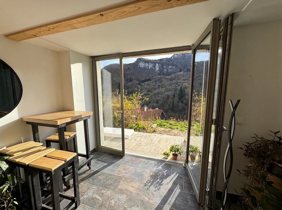 Fenêtre double vantail en bois massif naturel, encadrée de poutres en chêne brut aux formes organiques sculptées